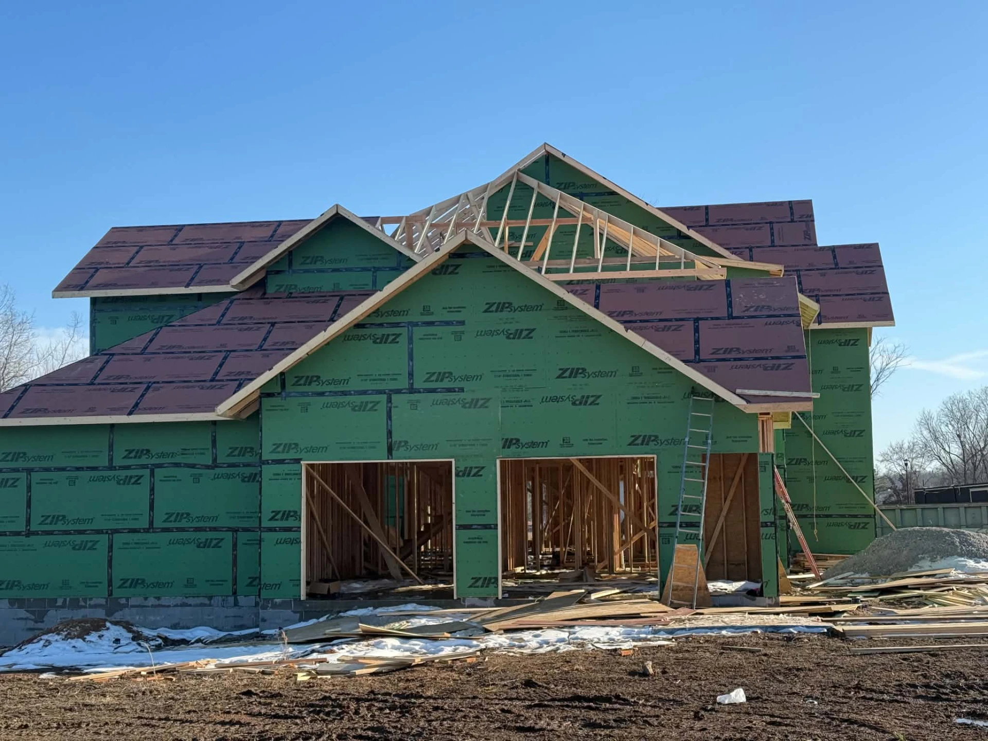 Multi-gable residence with roof trusses being set on a winter jobsite