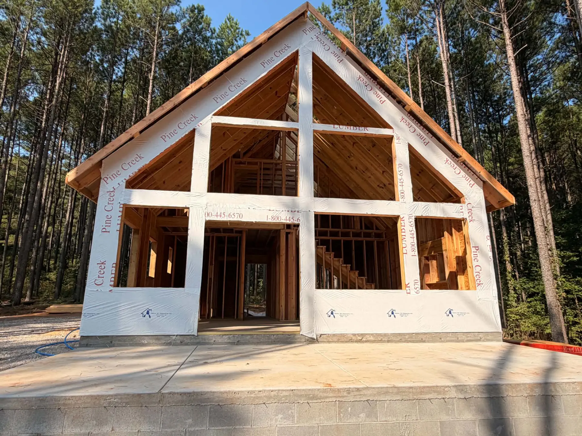 A-frame style cabin framed in the pines with tall gable window wall
